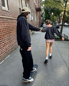 a man and woman are holding hands on a skateboard