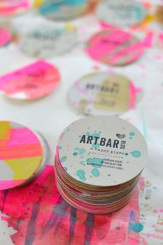 several round coasters sitting on top of a table covered in paint splattered paper