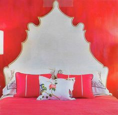 a bedroom with red walls and white headboard, pink bedding, and pillows