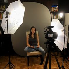 a woman sitting on a chair in front of a camera set up for a photo shoot