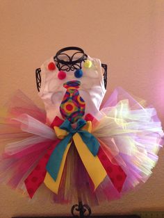 a white shirt and colorful tutu skirt on top of a stand with a light pink wall in the background