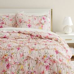 a white bed with pink and yellow floral comforter set on it's side