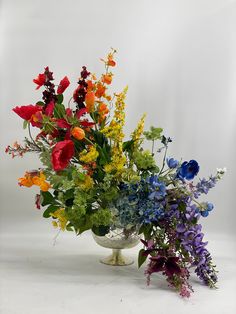 a vase filled with lots of colorful flowers on top of a white tablecloth covered floor