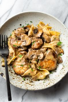 a white plate topped with pasta covered in mushroom sauce