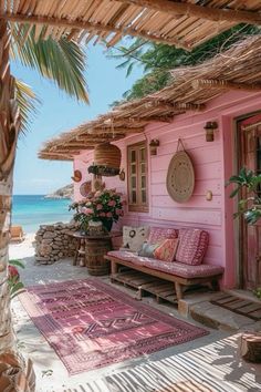 a pink house on the beach with an area rug and potted plants next to it