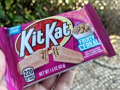 a hand holding a pink kitkat cereal bar