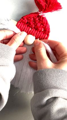 two hands are holding yarn and crochet together to make a heart ornament