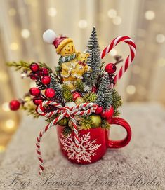 a red mug filled with candy canes and christmas decorations