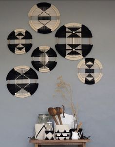 nordic woven wall hangings in black, white and pink are on display against a gray wall