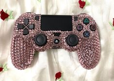 a close up of a nintendo wii game controller on a bed covered in rose petals