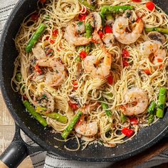 pasta with shrimp, asparagus and peppers in a skillet on a wooden table