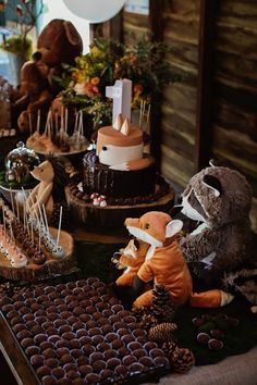 there are many stuffed animals on the table with cakes and cupcakes in front of them