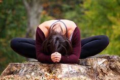 a woman sitting on top of a tree stump in the middle of her body, with her hands behind her head