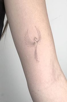 a woman's arm with a small bird tattoo on the back of her left arm