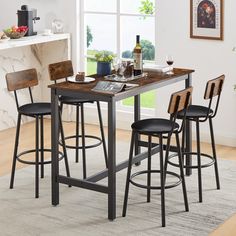 a kitchen table with four stools and a wine bottle on the counter top in front of a window