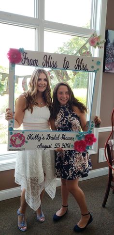 two women standing next to each other in front of a window holding up a sign that says from miss to mrs