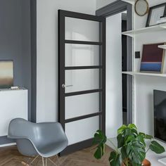 a living room with a chair, television and bookshelf on the wall in front of it