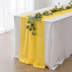 a yellow and white table cloth with flowers on it is sitting on a wooden floor