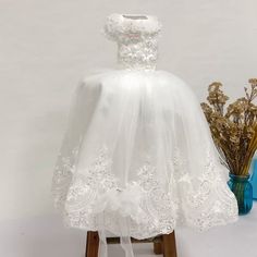 a white dress is sitting on a wooden stand