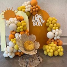 an orange and white balloon arch with the word happy on it, surrounded by balloons