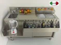 a stainless steel counter with bottles and blenders on it, next to a sink