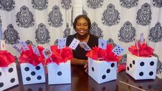 a woman sitting at a table with four dice boxes in front of her and red bows on them