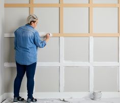 an older woman is painting the walls in her living room with white paint and she's holding a brush