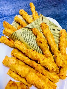 fried chicken sticks on a plate with newspaper wrapper next to them, ready to be eaten