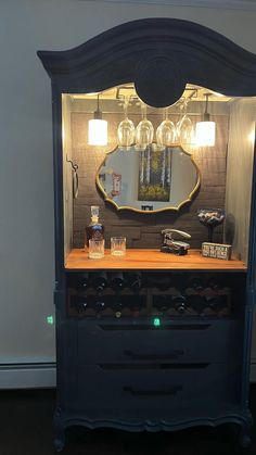 an old dresser with wine glasses on top and a mirror above it in a room