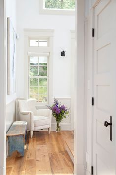 a white chair sitting next to a window in a room with wooden floors and walls