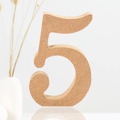 the number five is made out of wood and sits next to a vase with flowers