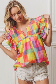 Woven Smocked Detail Top Experience a burst of color with this printed woven top featuring smocked detailing and ruffled sleeves. The V neck adds a touch of style to this playful and fun piece. Trendy Smocked Top For Beach, Playful Ruffle Sleeve Tops For Spring, Playful Summer Blouse With Ruffles, Playful Ruffled Blouse For Summer, Multicolor Ruffled Tops For Day Out, Trendy Multicolor Smocked Top With Smocked Back, Multicolor Ruffle Sleeve Tops For Vacation, Casual Multicolor Top With Smocked Bodice, Trendy Multicolor Smocked Top