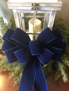 a large blue bow on top of a wooden table next to a candle and wreath