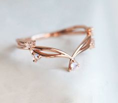 a rose gold ring with white stones on it's sides and leaves in the middle