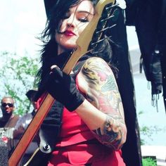 a woman with tattoos holding a guitar in her hands