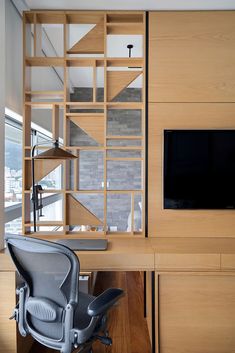 an office with a desk, chair and television on the wall next to it's built in bookshelf