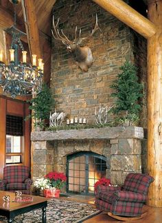 a living room with couches and chairs in front of a stone fire place that has deer heads mounted on the wall