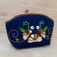 Hand-embroidered flower design in high relief on blue denim.    Dimensions: Length: 9 inches Width: 3 inches Height: 6 inches Blue Embroidered Rectangular Pouch, Embroidered Blue Pouch For Gifts, Embroidered Blue Pouch As Gift, Blue Embroidered Pouch For Gifts, Embroidered Blue Pouch For Gift, Blue Embroidered Pouch For Gift, Peruvian Embroidery, Pouch Embroidery, Handmade Makeup Bag