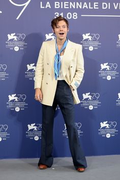 a man standing in front of a blue wall wearing a suit and tie with his mouth open