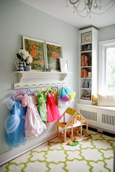 there are many dresses hanging on the rack in this child's room, and one is holding a doll