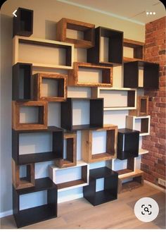 a book shelf made out of wood and some shelves on top of each other in front of a brick wall