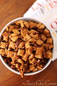 a white bowl filled with cereal on top of a wooden table next to a napkin