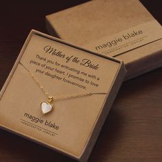 a heart shaped necklace sitting in a box on top of a wooden table next to a card