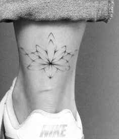 a black and white photo of a woman's foot with a flower tattoo on it