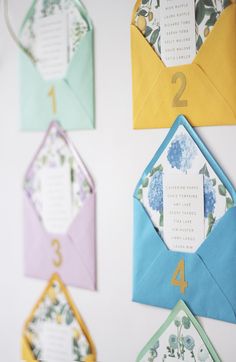 colorful envelopes with numbers and flowers on them hanging from the side of a wall