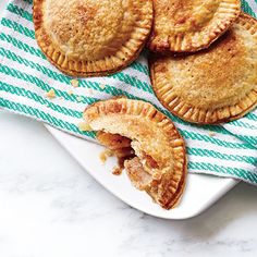 four small pies on a plate with a green and white towel