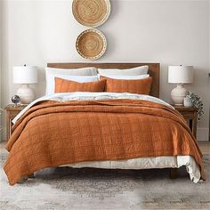 a bed with an orange comforter and pillows