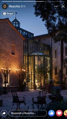 an outdoor area with chairs and tables lit up at night in front of a brick building