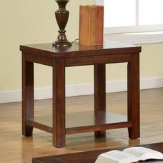 a small wooden table with an open book on it and a candle in the middle