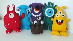 several stuffed toys are lined up in a row on a table, with eyes and mouths